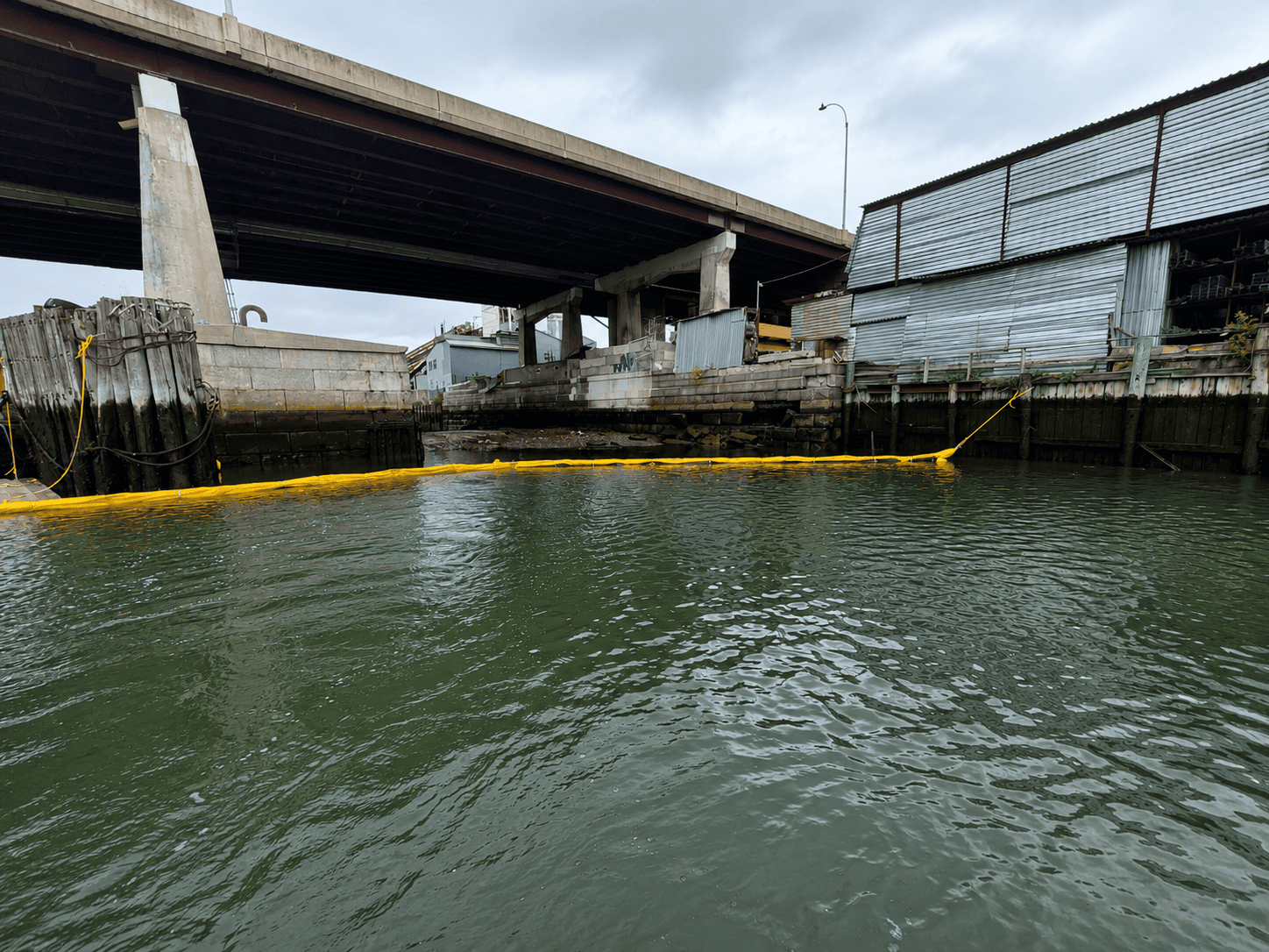 Type 1 Turbidity Curtain for Industrial Waterfront Sediment Control Type 1 Turbidity Curtain installed along an industrial waterfront beneath a bridge, creating a floating sediment control barrier around a marine work area.