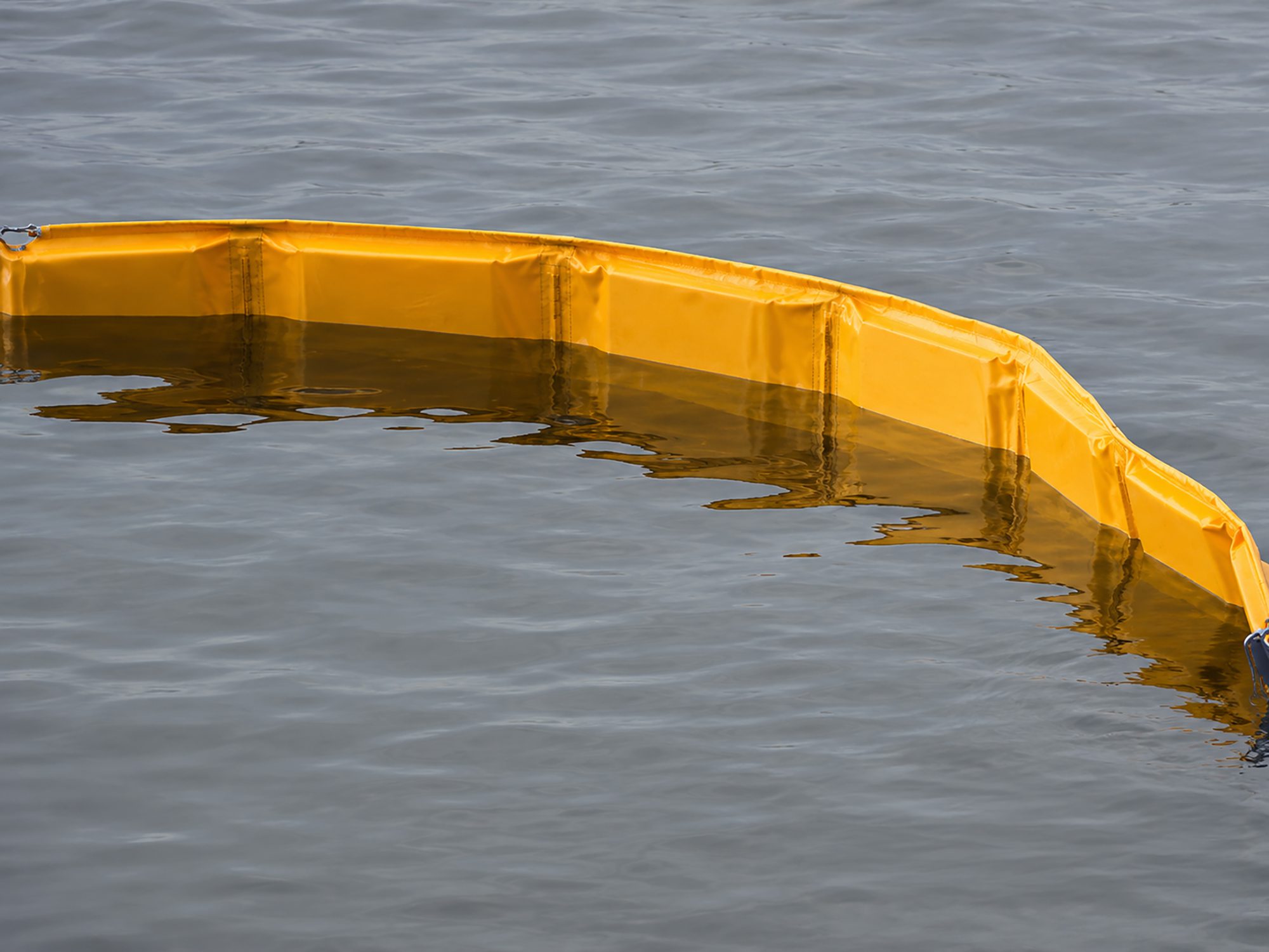 Yellow Oil Fence Boom deployed on the water to contain and control oil spills and other floating surface contaminants.