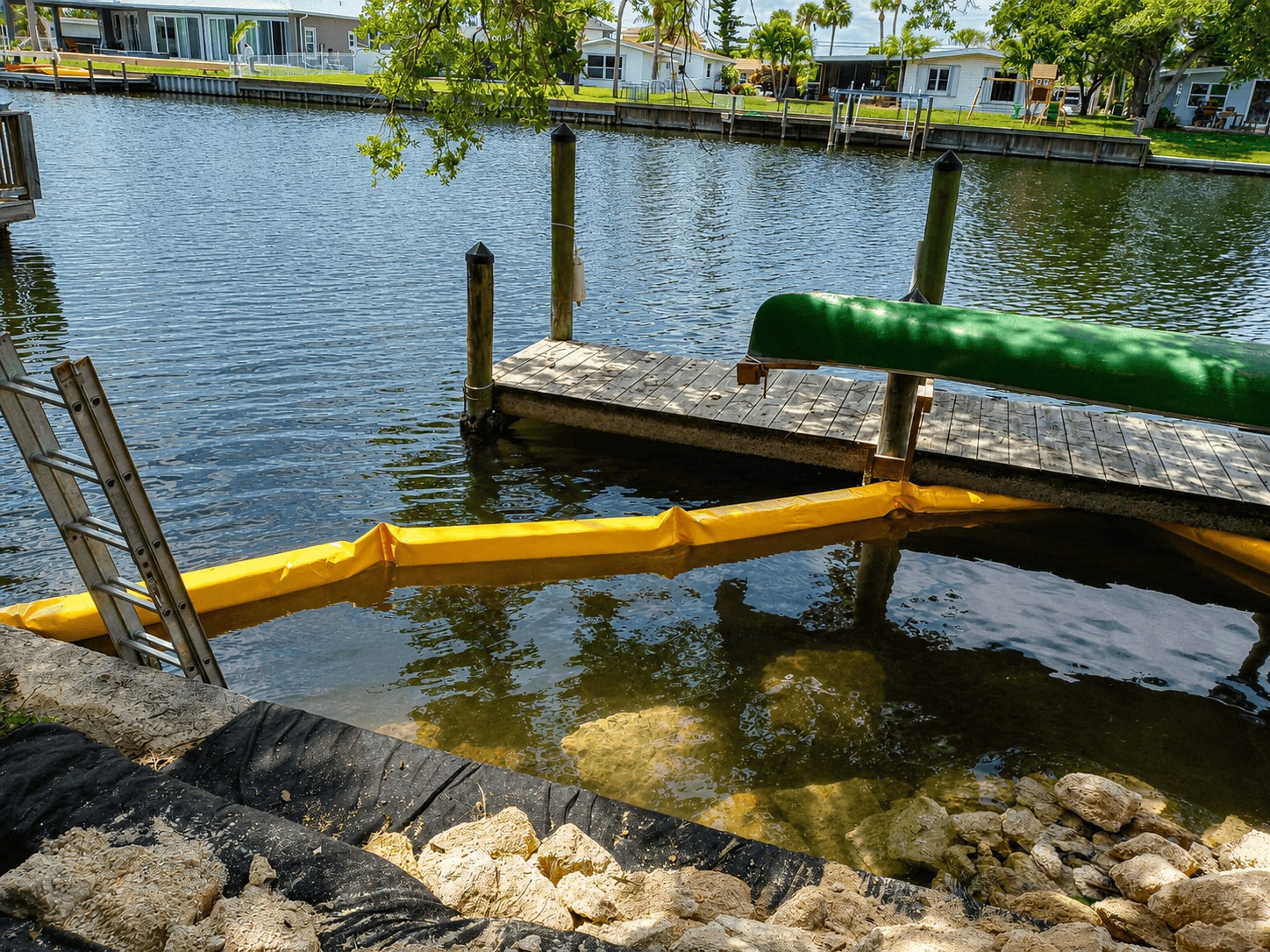 Type 1 Turbidity Curtain installed around a residential dock and shoreline work area in calm canal water to help contain sediment and turbidity.