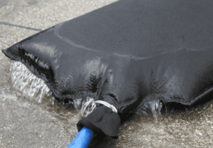 Dewatering bag filtering sediment-laden water as clean water drains through the geotextile fabric during construction site dewatering.
