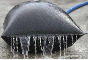Dewatering bag filtering sediment-laden water as clean water drains through the geotextile fabric during construction site dewatering.